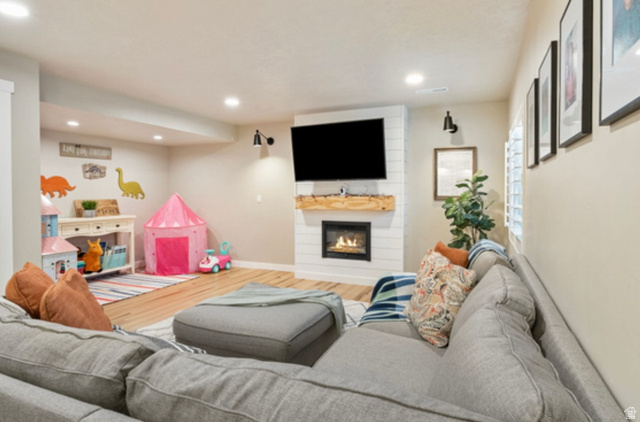 1295 East Granite Peak Road Eagle Mountain, UT 84005 - Photo 29 of 35 Living area featuring a shiplap-paneled fireplace with a wood mantle, an integrated television mount, and recessed lighting