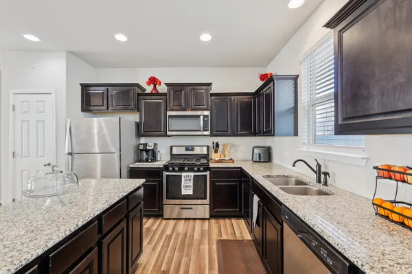 a kitchen with stainless steel appliances granite countertop a sink stove and refrigerator