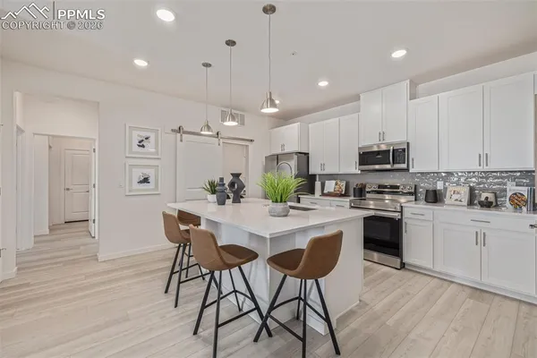 a kitchen with stainless steel appliances kitchen island granite countertop a wooden floor and white cabinets