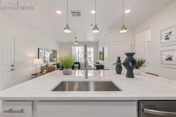 a kitchen with a sink a counter space and living room view