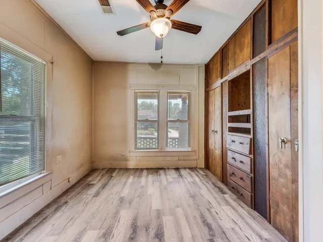 a view of an empty room with a window and wooden floor