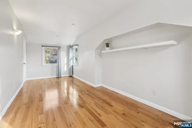 a view of empty room with wooden floor and windows