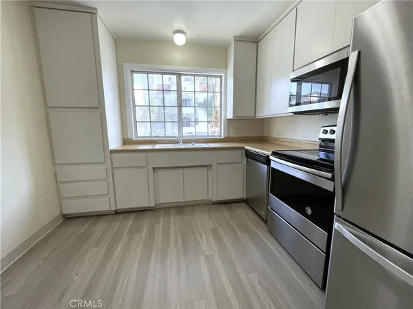 a kitchen with stainless steel appliances white cabinets and wooden floor