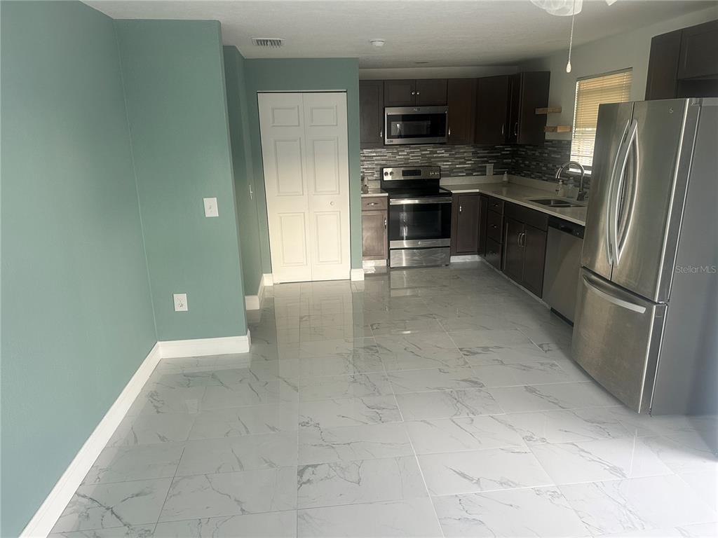 6740 Dairy Road Zephyrhills, FL 33542 - Photo 3 of 8 a kitchen with stainless steel appliances a refrigerator and a stove top oven