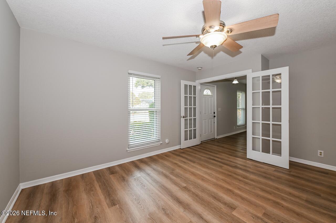 1077 Kings Road Neptune Beach, FL 32266 - Photo 7 of 19 an empty room with wooden floor chandelier fan and windows