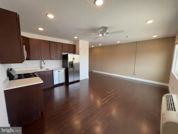 a open kitchen with stainless steel appliances granite countertop a refrigerator a stove and a wooden floors