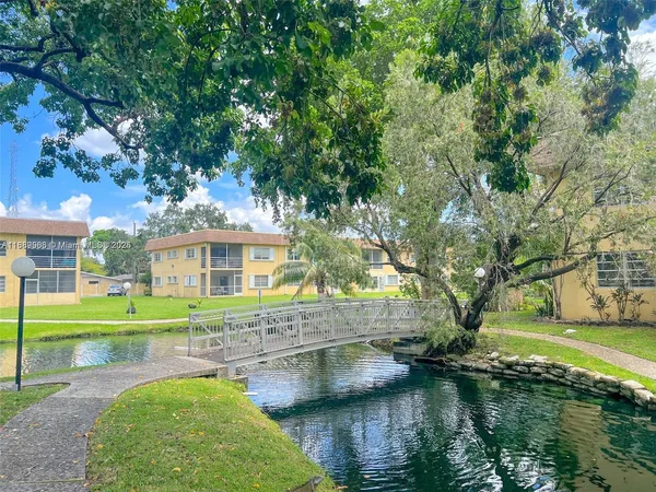 a view of a house with a yard and a large tree