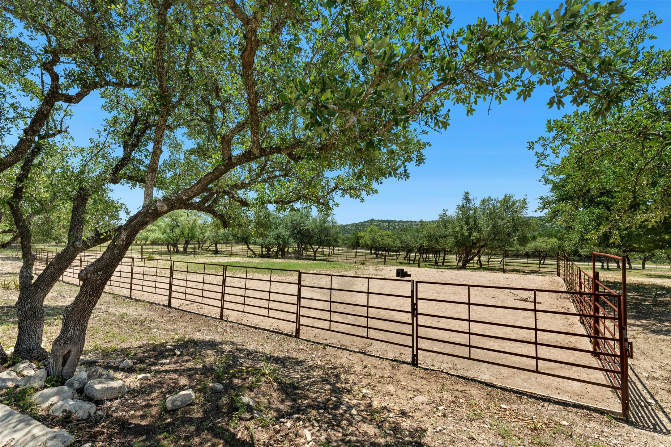 496 Middleton Road Spicewood, TX 78669 - Photo 33 of 40 Expansive outdoor area featuring mature trees, a metal perimeter fence, and a clear sky backdrop