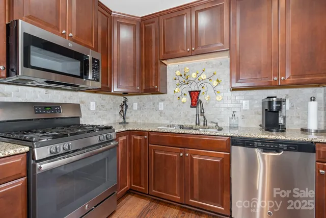 a kitchen with stainless steel appliances granite countertop a stove top oven a sink dishwasher and microwave oven