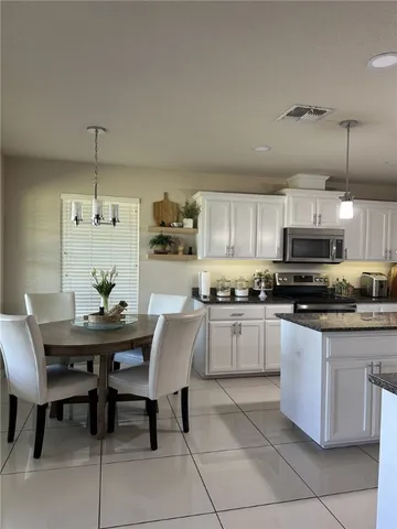 a kitchen with a dining table chairs and white cabinets