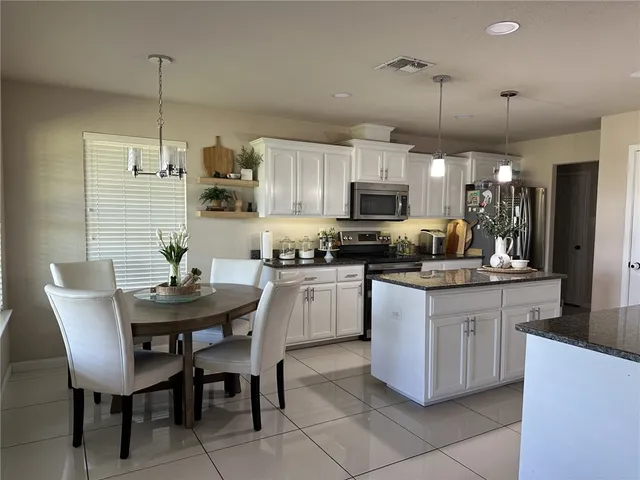 a kitchen with kitchen island granite countertop a table chairs sink and microwave