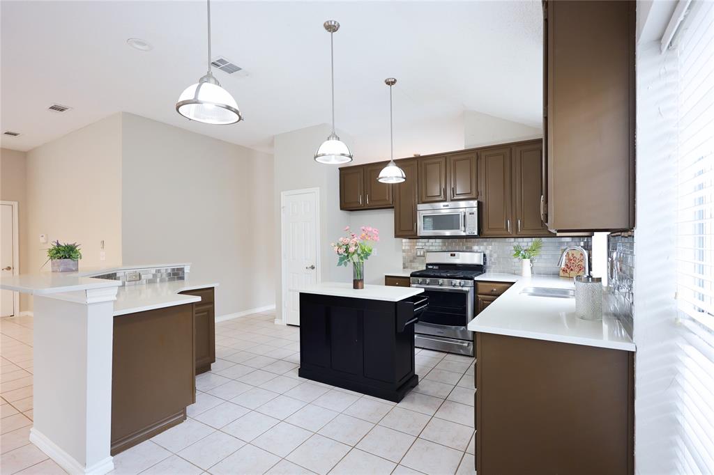 8112 Dock Street Frisco, TX 75035 - Photo 13 of 34 a kitchen with kitchen island granite countertop a sink counter top space appliances and cabinets