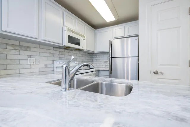 a kitchen with stainless steel appliances granite countertop a sink a refrigerator and a sink