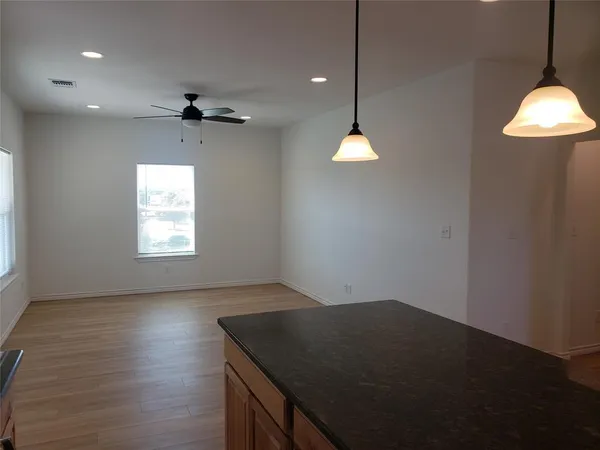 a kitchen with stainless steel appliances granite countertop a refrigerator a sink dishwasher a stove and white countertops with wooden floor