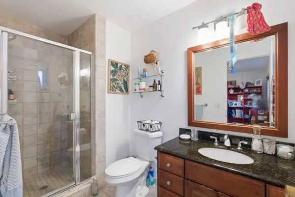 a bathroom with a granite countertop sink a toilet a shower and a mirror