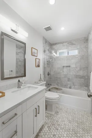 a bathroom with a double vanity sink toilet mirror and bathtub