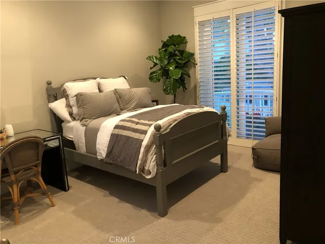 a bed sitting in a bedroom next to a window and a chair