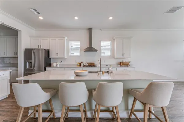 a kitchen with stainless steel appliances granite countertop a dining table chairs refrigerator and microwave