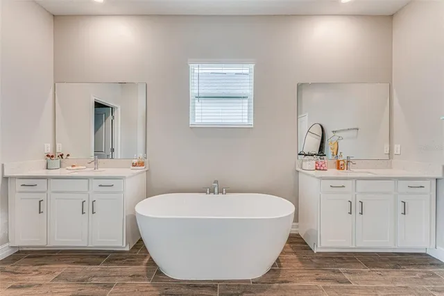 a spacious bathroom with a double vanity sink mirror and bathtub