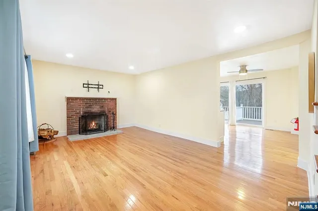 a view of an empty room with wooden floor fireplace and a window
