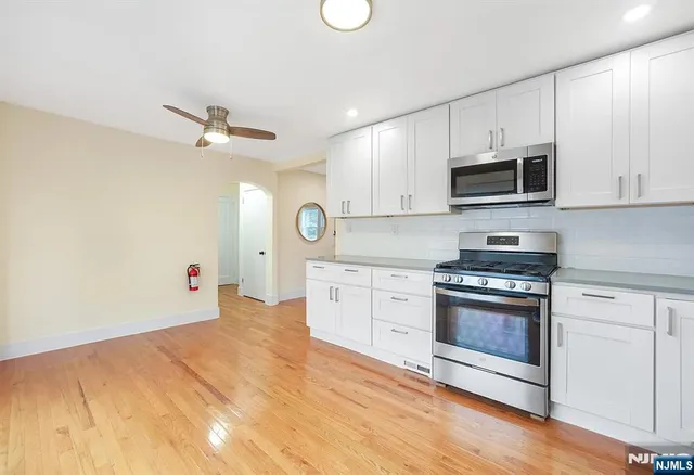 a kitchen with granite countertop a stove a sink and white cabinets