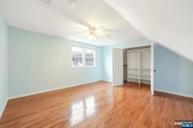 an empty room with wooden floor ceiling fan and windows