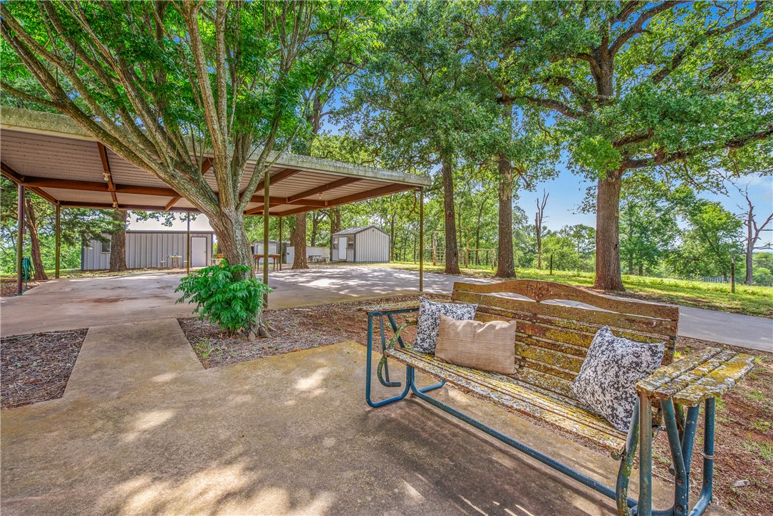 1110 County Road 439 Dime Box, TX 77853 - Photo 47 of 50 a view of a patio with couches and table and chairs under an umbrella with large trees