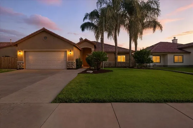 a front view of a house with a garden and trees