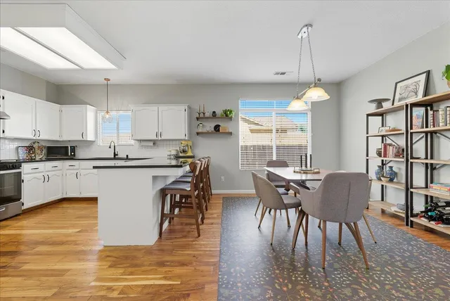 a kitchen with stainless steel appliances granite countertop a table chairs sink and cabinets