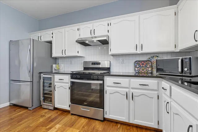 a kitchen with cabinets stainless steel appliances and wooden floor
