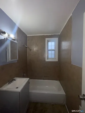 a bathroom with a tub sink and mirror