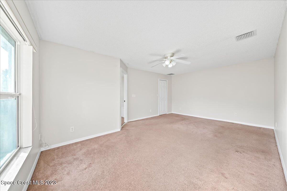 590 Fountain Street Southwest Palm Bay, FL 32908 - Photo 22 of 40 an empty room with a chandelier fan and windows