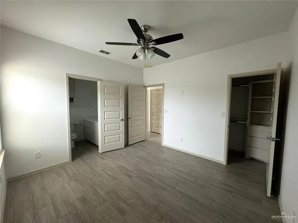 a view of empty room with wooden floor and ceiling fan