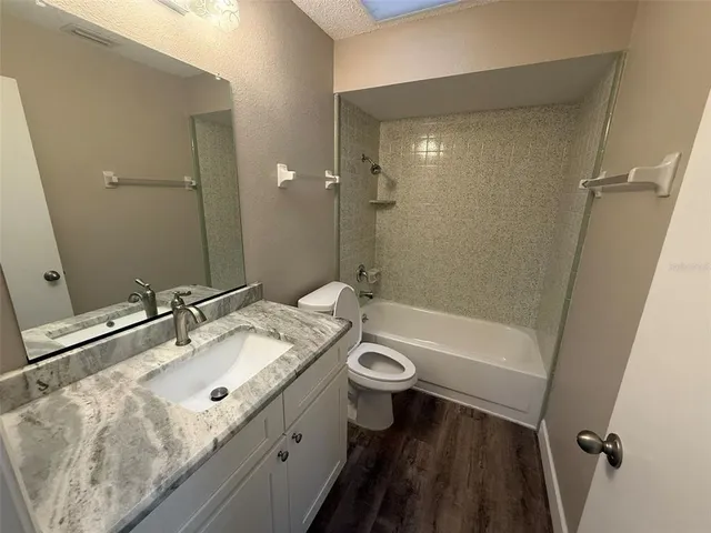 a bathroom with a granite countertop sink a toilet and shower