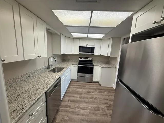 a kitchen with granite countertop a refrigerator a sink and dishwasher