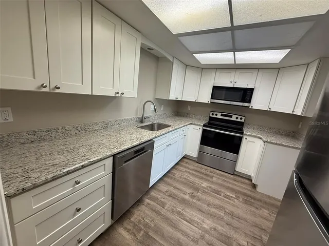 a kitchen with stainless steel appliances granite countertop a sink a stove and a microwave