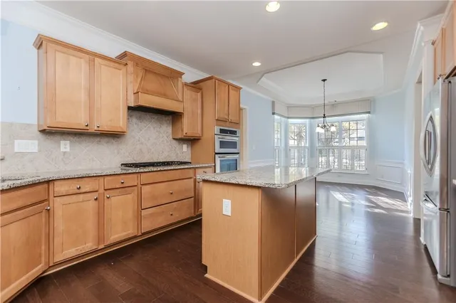 a kitchen with stainless steel appliances granite countertop a stove a sink and white cabinets with wooden floor