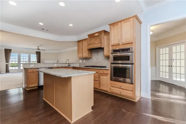 a kitchen with stainless steel appliances kitchen island granite countertop a stove a sink and a refrigerator
