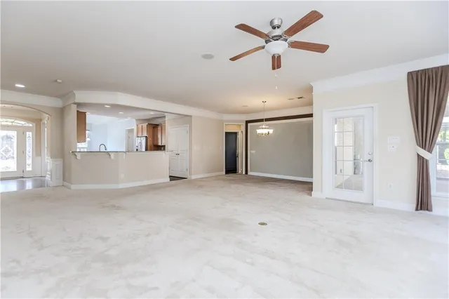 a view of a livingroom with a ceiling fan a kitchen space with wooden floors and a ceiling fan