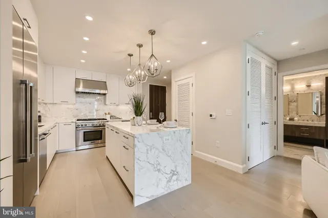a large kitchen with kitchen island white cabinets and stainless steel appliances