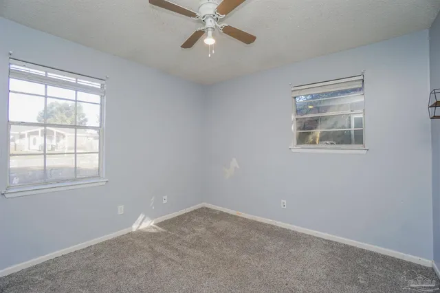an empty room with a window and a fan