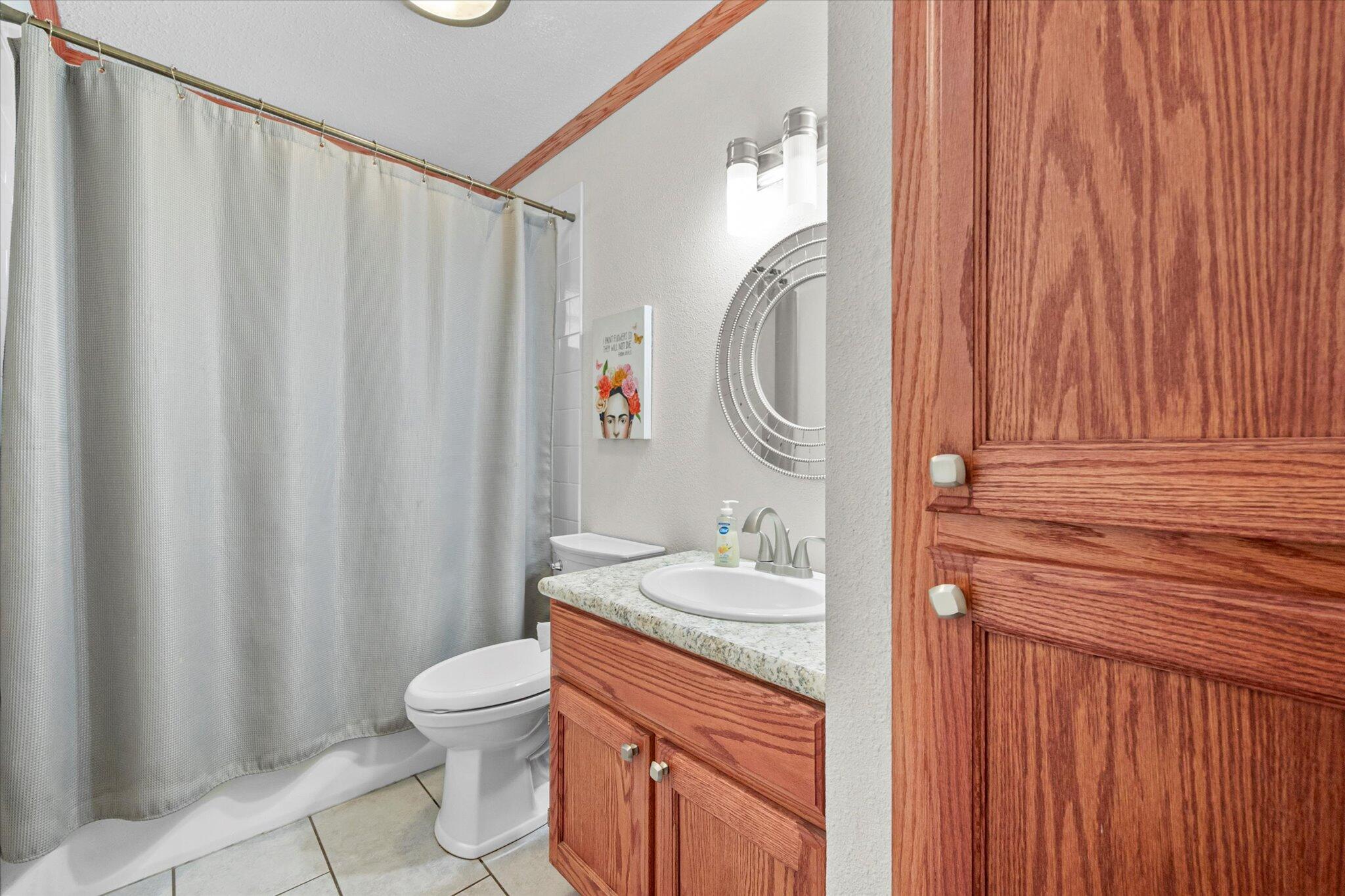 4824 8th Street Lubbock, TX 79416 - Photo 20 of 27 a bathroom with a granite countertop sink toilet and a mirror