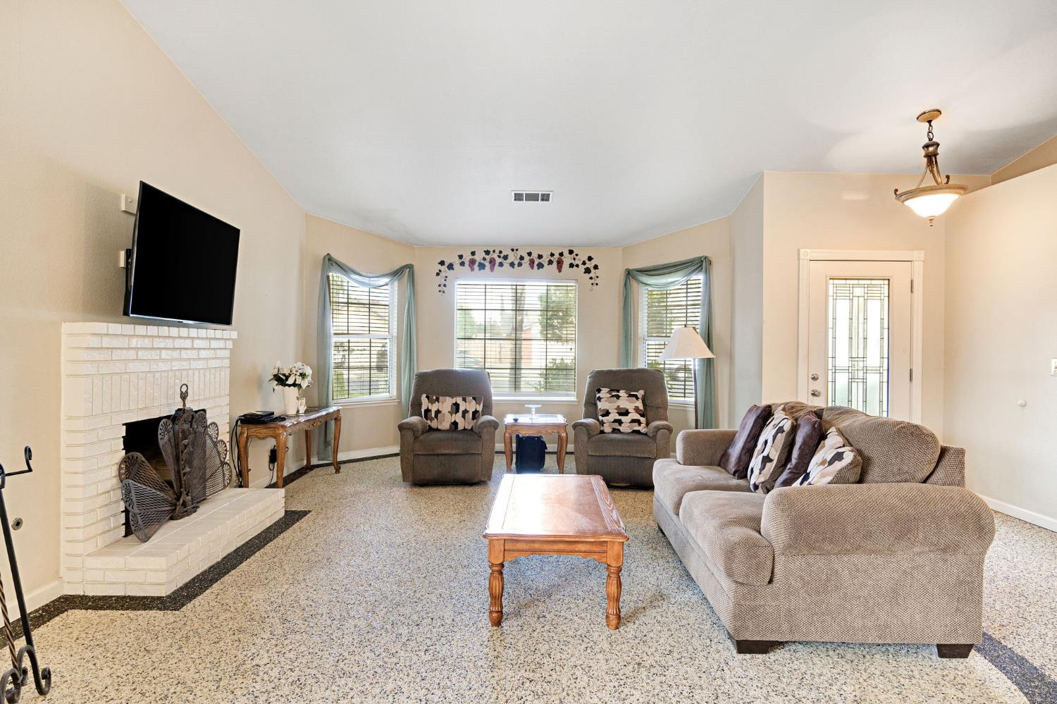 73 Devon Drive Lemoore, CA 93245 - Photo 13 of 32 a living room with fireplace furniture and a flat screen tv
