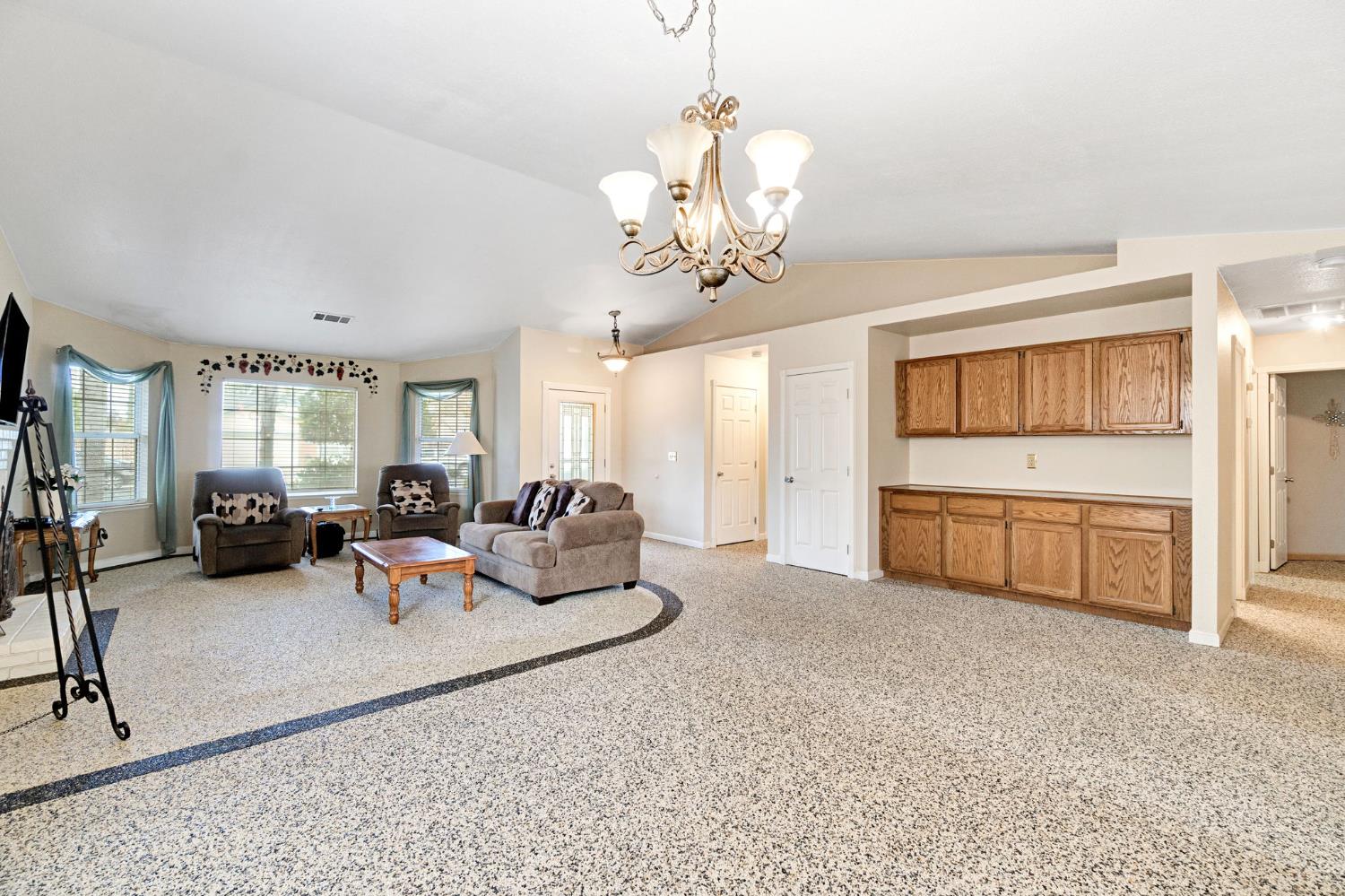 73 Devon Drive Lemoore, CA 93245 - Photo 10 of 32 a living room with furniture a chandelier and a flat screen tv