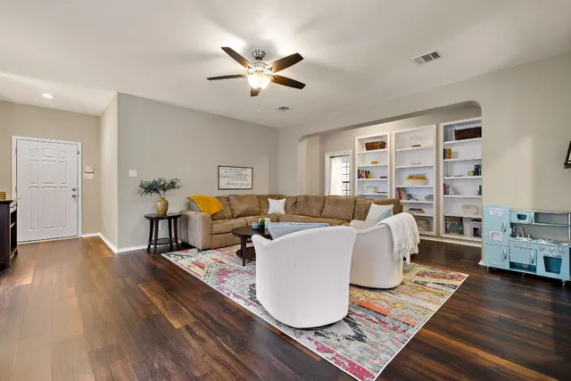 a living room with furniture large window and wooden floor