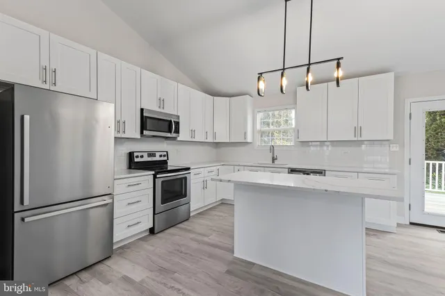 a kitchen with cabinets stainless steel appliances and wooden floor