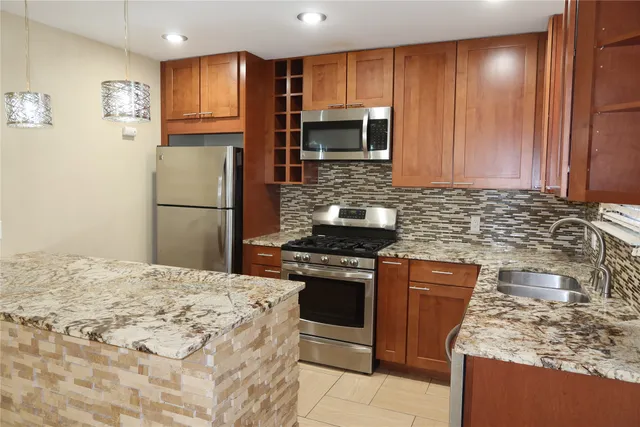 a kitchen with stainless steel appliances granite countertop a stove a refrigerator and a sink