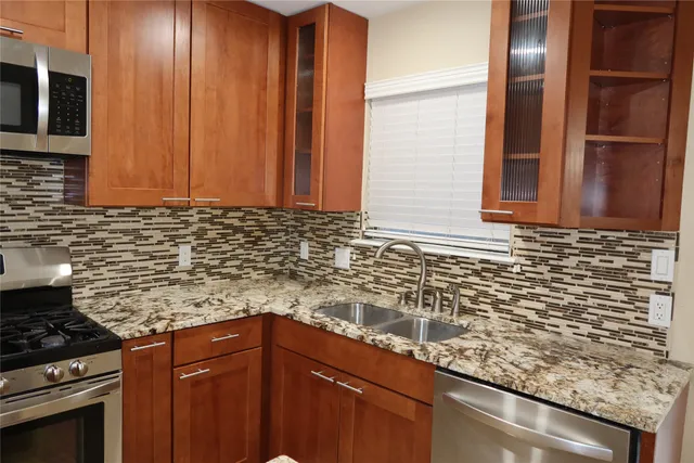 a kitchen with granite countertop a sink a stove and cabinets