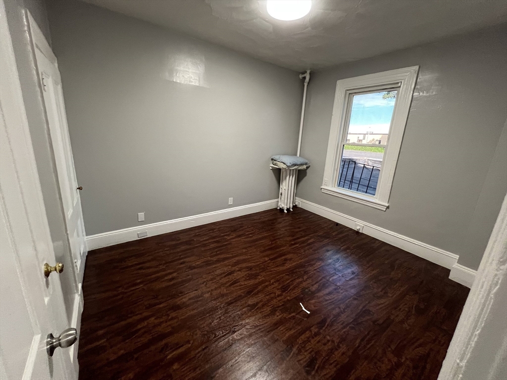 64 Hollis Street, Unit 13 Framingham, MA 01702 - Photo 2 of 7 an empty room with wooden floor and windows