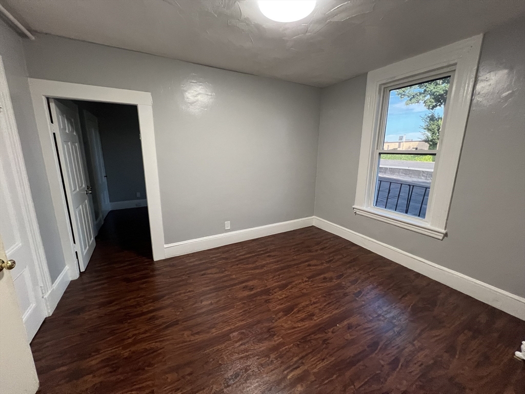 64 Hollis Street, Unit 13 Framingham, MA 01702 - Photo 4 of 7 a view of an empty room with wooden floor and a window